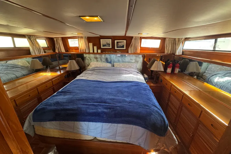Slide: The Image of Cozy bedroom interior of 1987 Lien Hwa 47 Cockpit Motoryacht with wooden cabinetry and blue bedding. - 19