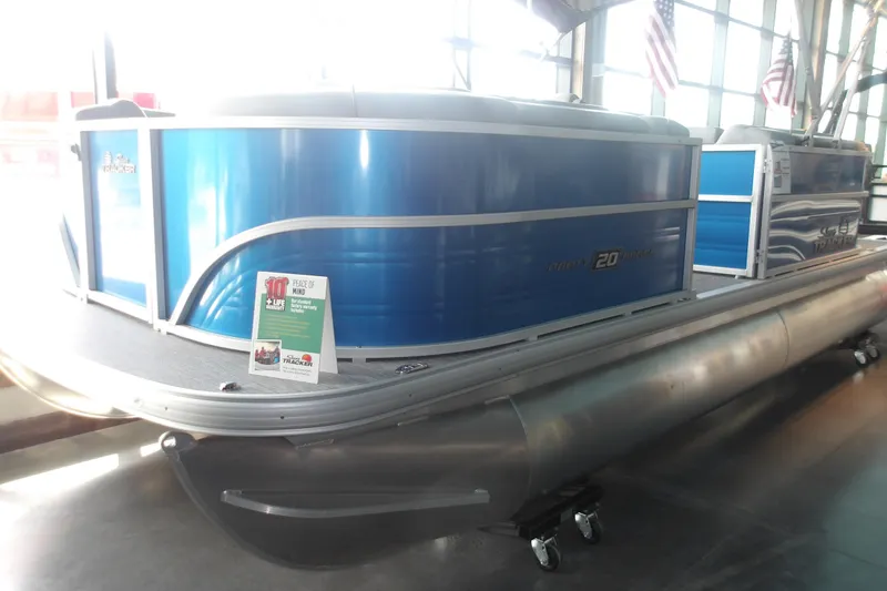 Slide: The Image of 2026 Sun Tracker Party Barge 20 DLX pontoon boat displayed indoors with promotional signage. - 8
