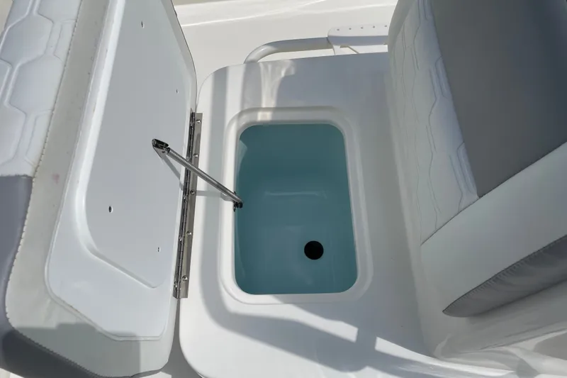 Slide: The Image of Open storage compartment on 2026 Mako 18 Pro Skiff boat, featuring a cushioned seat. - 13