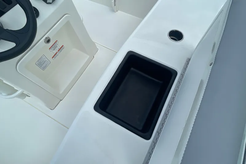 Slide: The Image of Interior view of 2026 Mako 18 Pro Skiff boat, featuring steering wheel and storage compartment. - 17