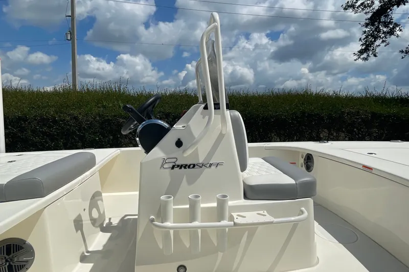 Slide: The Image of 2026 Mako 18 Pro Skiff boat interior with steering console and seating under cloudy sky. - 8