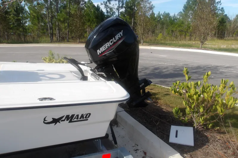 Slide: The Image of 2026 Mako Pro Skiff 13 CC with Mercury outboard motor parked near greenery. - 2