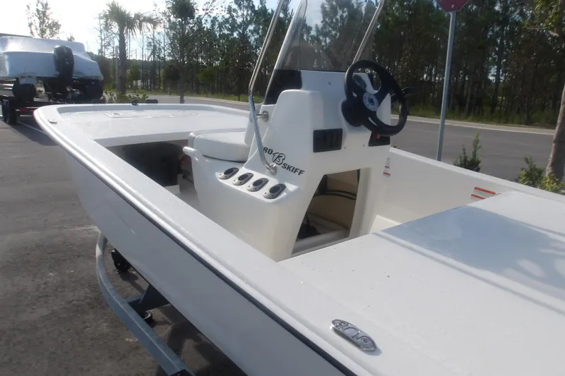 Slide: The Image of 2026 Mako Pro Skiff 13 CC boat with center console and steering wheel, parked outdoors. - 9