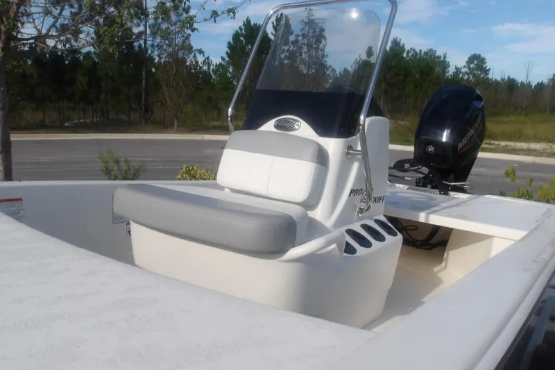 Slide: The Image of 2026 Mako Pro Skiff 13 CC boat with console and seating, parked outdoors. - 11