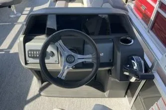 Slide: The Image of 2026 Sun Tracker Fishin' Barge 20 DLX steering console with controls and cup holder. - 5