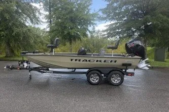 The Image of 2026 Tracker Pro Team 195 boat on trailer, parked outdoors with trees in the background. - 0