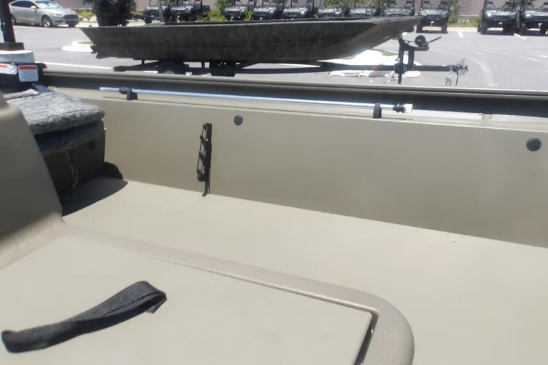Slide: The Image of 2026 Tracker Grizzly 1754 SC boat interior with seating and storage, parked outdoors. - 11