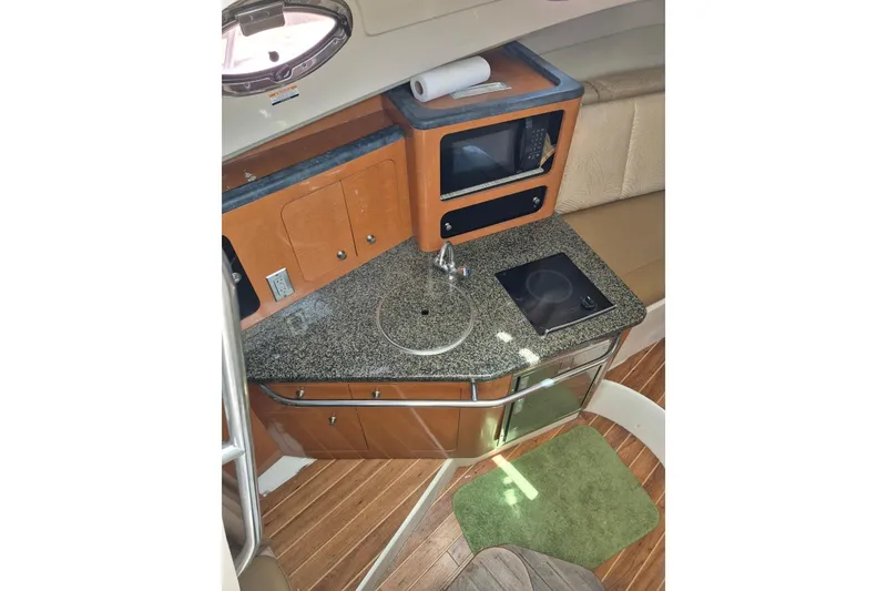 Slide: The Image of 2008 Robalo R305 Walkaround cabin kitchen with granite countertop, sink, and microwave. - 13