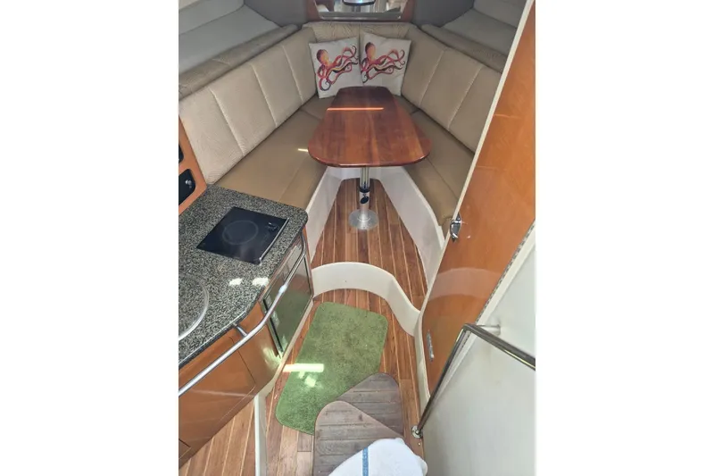 Slide: The Image of 2008 Robalo R305 Walkaround cabin interior with kitchenette, seating, and wooden table. - 12
