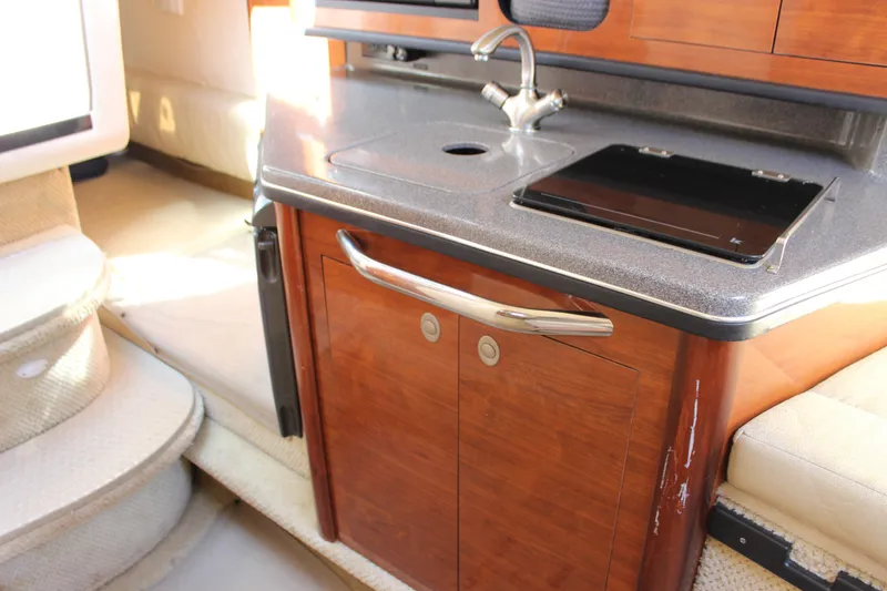 Slide: The Image of Interior of 2006 Sea Ray Sundancer 260, featuring a compact kitchenette with wood cabinetry. - 27