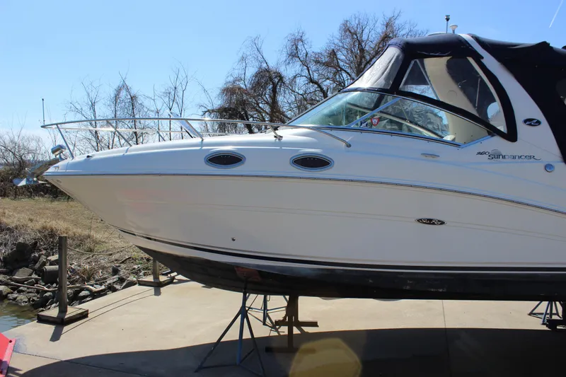 Slide: The Image of 2006 Sea Ray Sundancer 260 boat on dry dock, side view with trees in background. - 3