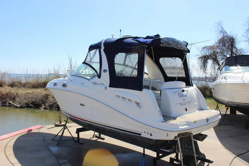 Slide: The Image of 2006 Sea Ray Sundancer 260 boat on dry dock, featuring a sleek design and navy canopy. - 5