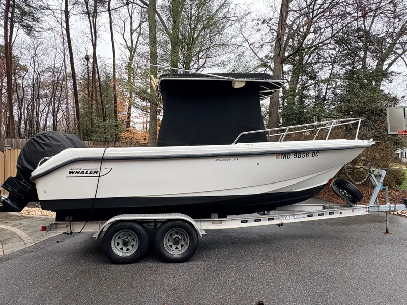 Slide: The Image of 1999 Boston Whaler 230 Outrage on trailer parked in wooded area. - 10