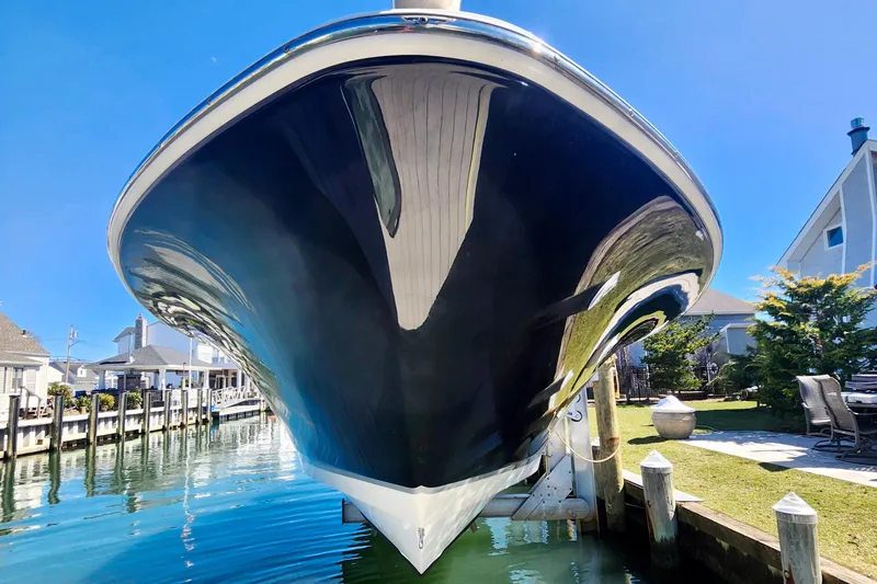 Slide: The Image of 2014 Wellcraft 35 Scarab Sport boat docked, reflecting in calm water under clear blue sky. - 30