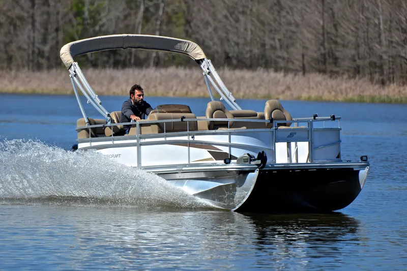 The Image of 2023 Starcraft EX 18 F pontoon boat cruising on a calm lake. - 1