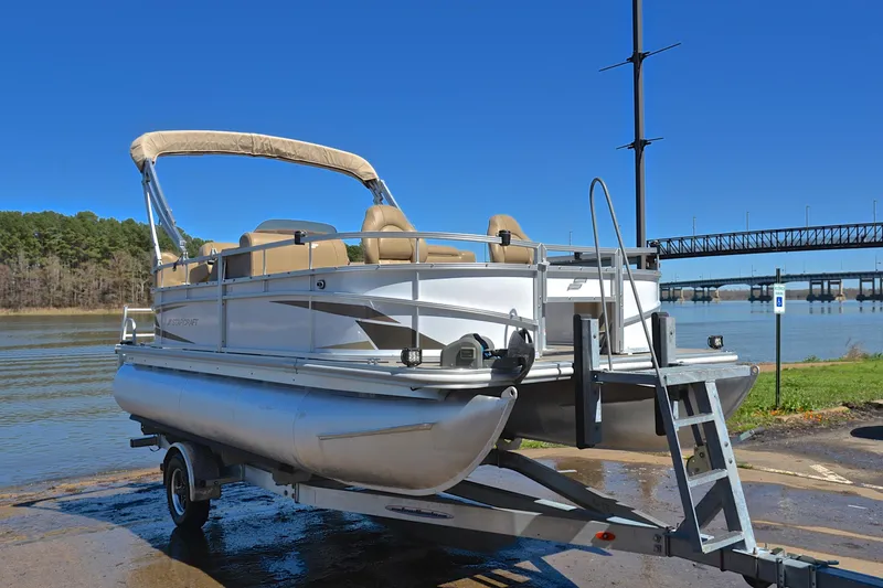 Slide: The Image of 2023 Starcraft EX 18 F pontoon boat on trailer by a river with bridge. - 16