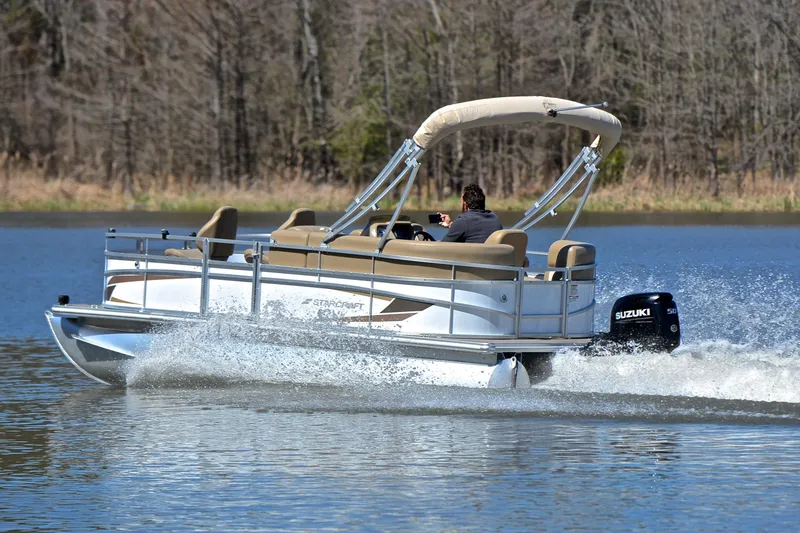 Slide: The Image of 2023 Starcraft EX 18 F pontoon boat cruising on a lake with Suzuki outboard motor. - 4