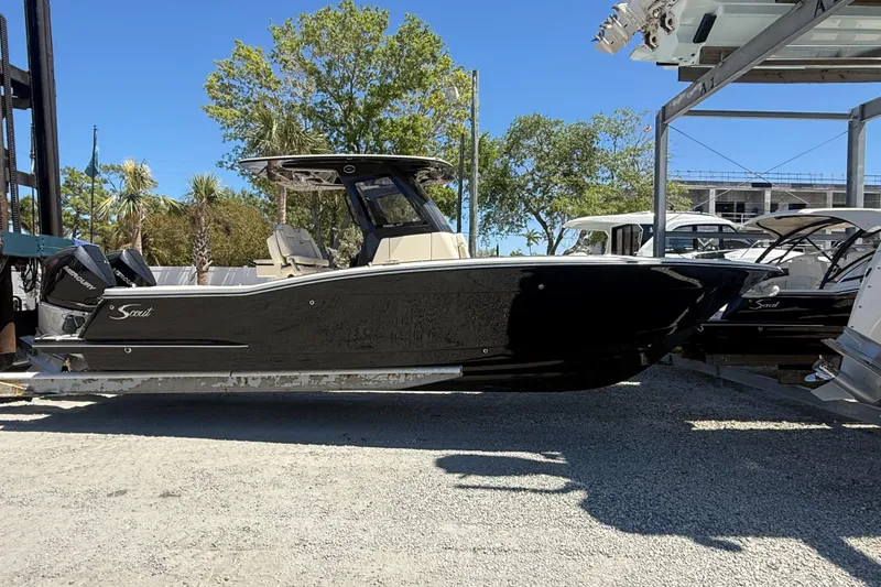 The Image of 2026 Scout 288 LXF boat in storage, black hull, outdoor setting. - 1