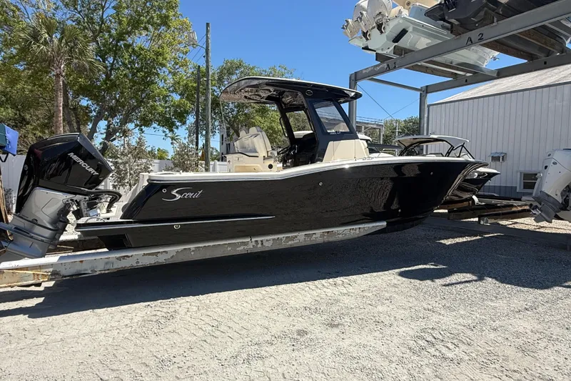 Slide: The Image of 2026 Scout 288 LXF boat with Mercury engine on a trailer, outdoors. - 2