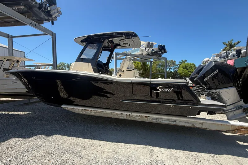 Slide: The Image of 2026 Scout 288 LXF boat with Mercury engines, parked outdoors under clear blue sky. - 8