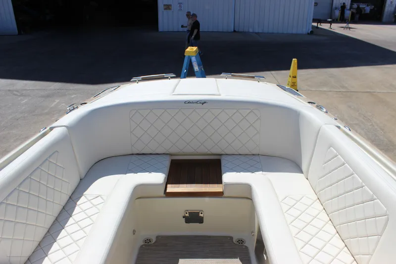 Slide: The Image of 2024 Chris-Craft Launch 27 boat interior with white quilted seating and wooden table. - 25