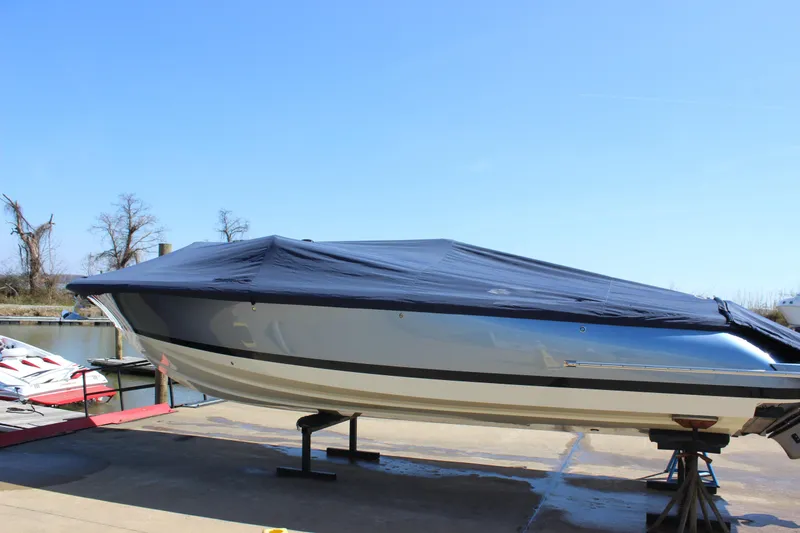 Slide: The Image of 2024 Chris-Craft Launch 27 boat covered, docked at marina under clear blue sky. - 27