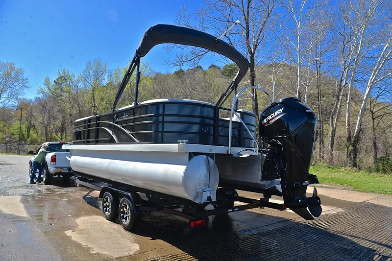 Slide: The Image of 2022 Bennington 22 L pontoon boat on trailer with Mercury engine, outdoors. - 12