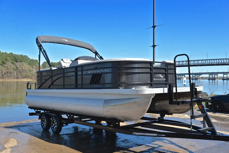 Slide: The Image of 2022 Bennington 22 L pontoon boat on trailer by a lake. - 16