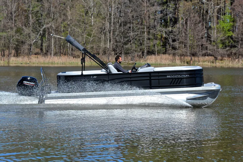Slide: The Image of 2022 Bennington 22 L pontoon boat cruising on a lake with Mercury outboard motor. - 3