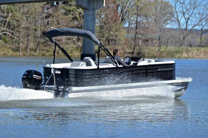 Slide: The Image of 2022 Bennington 22 L pontoon boat cruising on a lake with a Mercury engine. - 5