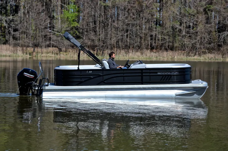 Slide: The Image of 2022 Bennington 22 L pontoon boat cruising on a calm lake. - 6