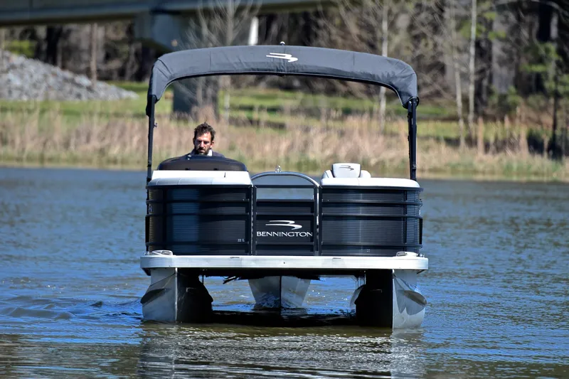 Slide: The Image of 2022 Bennington 22 L pontoon boat cruising on a calm lake. - 9