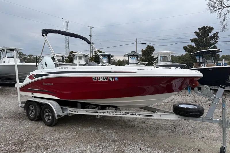 Slide: The Image of 2022 Hurricane SunDeck Sport 205 OB boat on trailer, red and white design, parked outdoors. - 11
