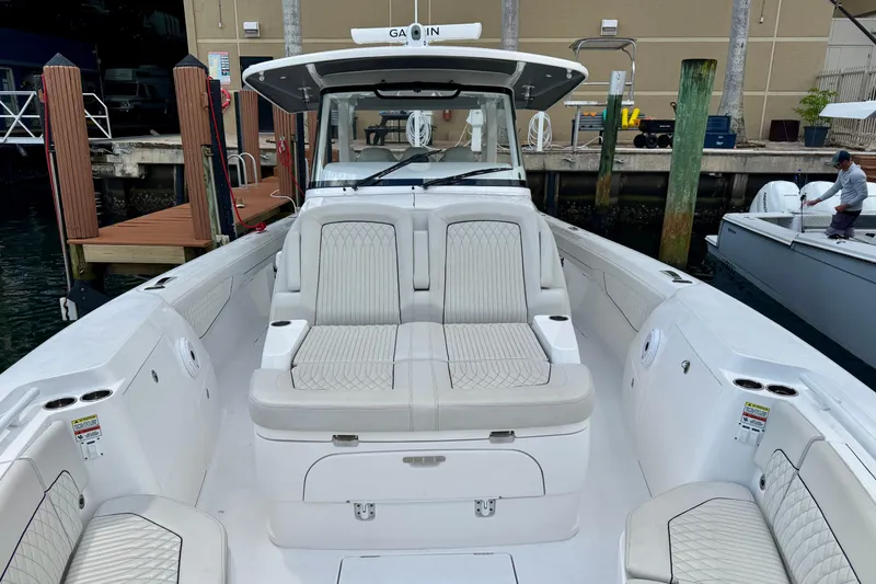 Slide: The Image of 2024 Intrepid 427 Nomad SE boat with luxurious seating at a marina dock. - 10