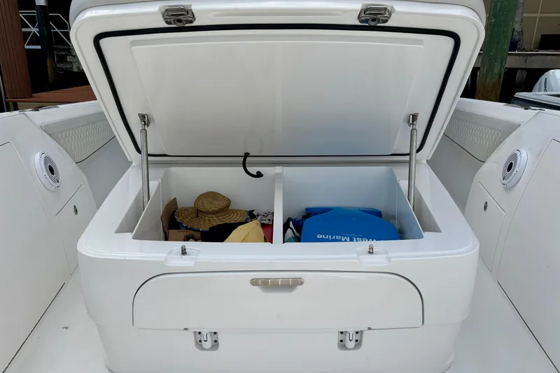 Slide: The Image of Open storage compartment on 2024 Intrepid 427 Nomad SE boat, containing hats and bags. - 12