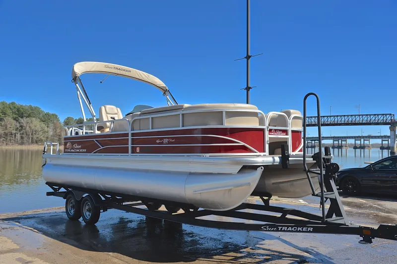 Slide: The Image of 2019 Sun Tracker SportFish 22 DLX pontoon boat on trailer by a lake. - 16