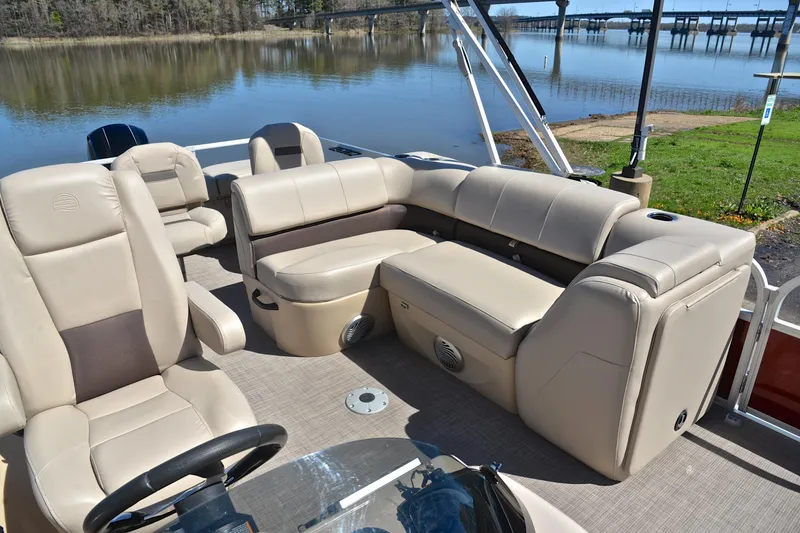 Slide: The Image of 2019 Sun Tracker SportFish 22 DLX pontoon boat with beige seating, docked by a serene lake. - 22