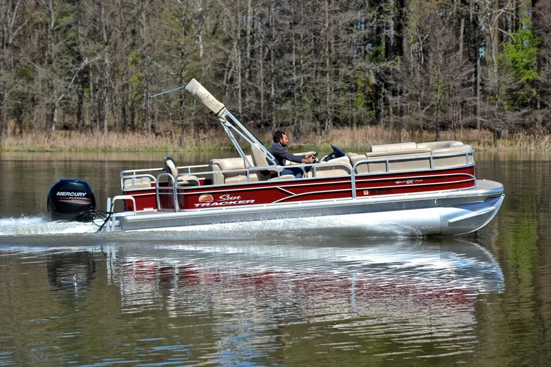 Slide: The Image of 2019 Sun Tracker SportFish 22 DLX pontoon boat cruising on a calm lake. - 3