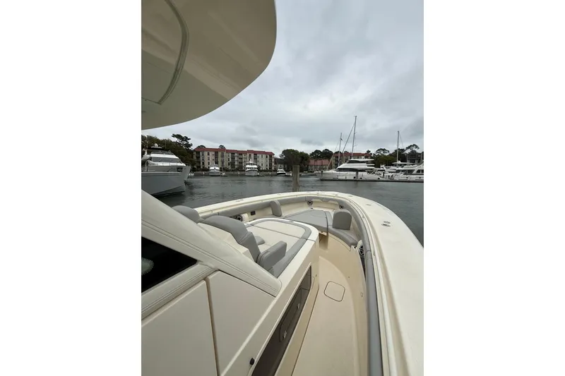 Slide: The Image of 2021 Scout 355 LXF boat docked in a marina with surrounding yachts. - 12