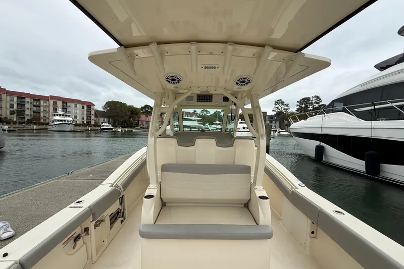 Slide: The Image of 2021 Scout 355 LXF boat interior at marina, showcasing seating and helm area. - 13