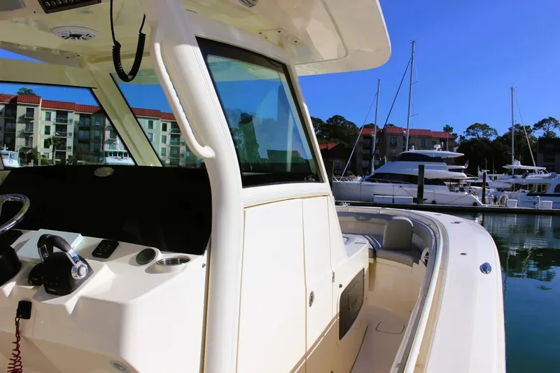 Slide: The Image of 2021 Scout 355 LXF boat docked in marina, showcasing helm and seating area. - 6