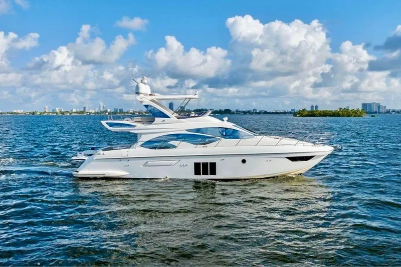 Slide: The Image of 2016 Azimut 54 yacht cruising on a sunny day with city skyline backdrop. - 4