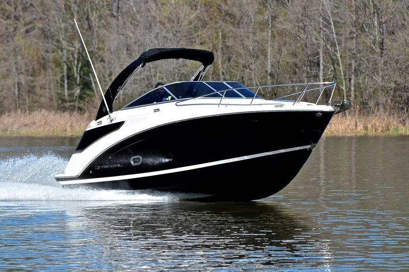 The Image of 2016 Regal 26 Express boat cruising on a calm lake with forest backdrop. - 1
