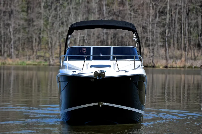 Slide: The Image of 2016 Regal 26 Express boat cruising on a calm lake with forest backdrop. - 11
