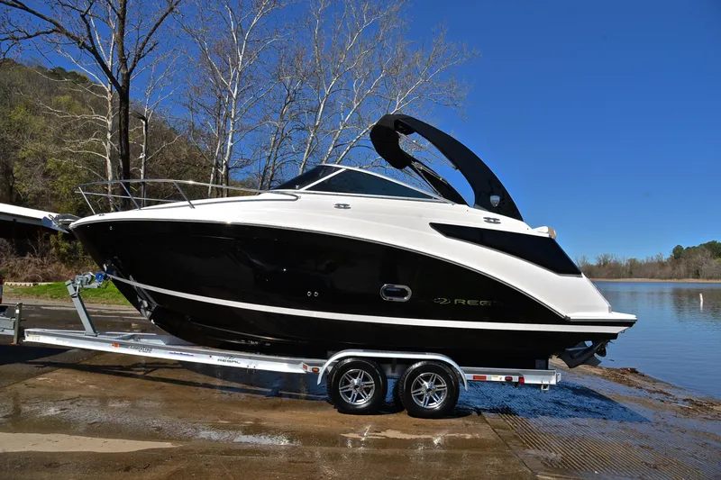 Slide: The Image of 2016 Regal 26 Express boat on trailer by a lake, clear blue sky. - 13