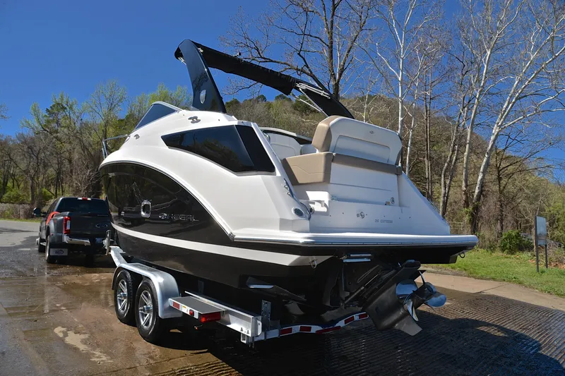 Slide: The Image of 2016 Regal 26 Express boat on trailer, parked near trees and a truck. - 14