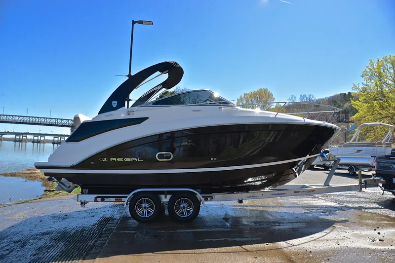 Slide: The Image of 2016 Regal 26 Express boat on trailer by a river under clear blue sky. - 17