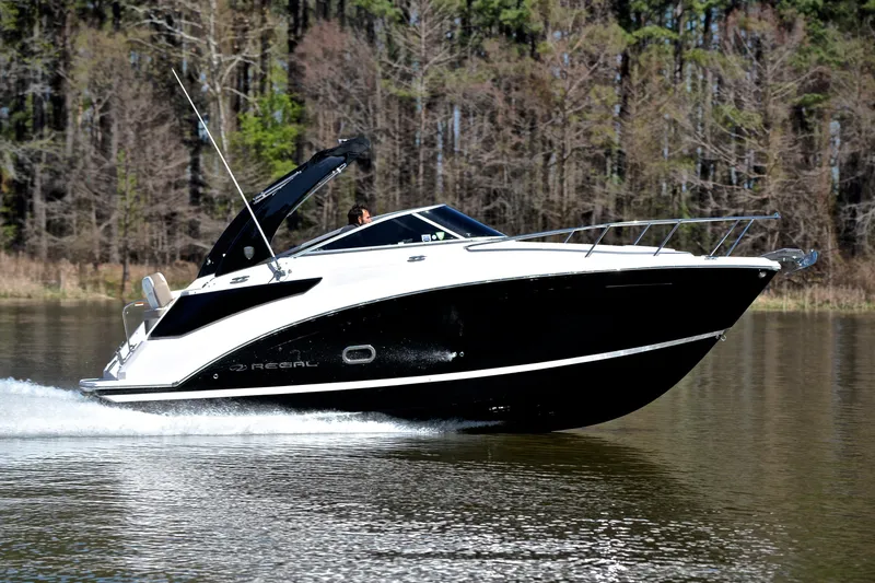 Slide: The Image of 2016 Regal 26 Express boat cruising on a calm lake with forest backdrop. - 3