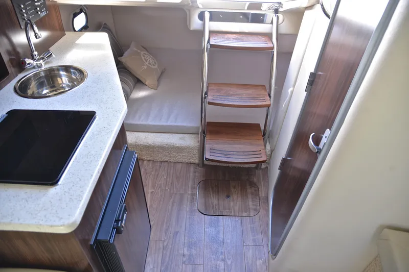 Slide: The Image of 2016 Regal 26 Express cabin interior with kitchenette, wooden steps, and cozy seating area. - 31