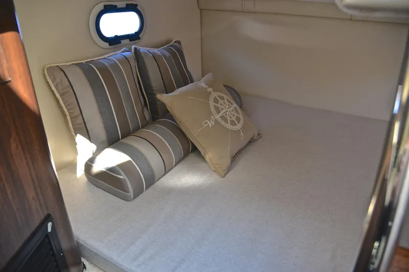 Slide: The Image of Cozy cabin interior of 2016 Regal 26 Express with striped and compass-themed pillows. - 32